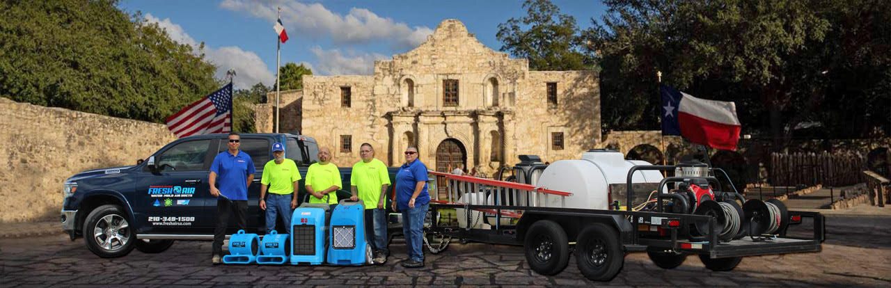 Fresh Air crew with a company truck, equipment trailer and air movers in front of the Alamo
