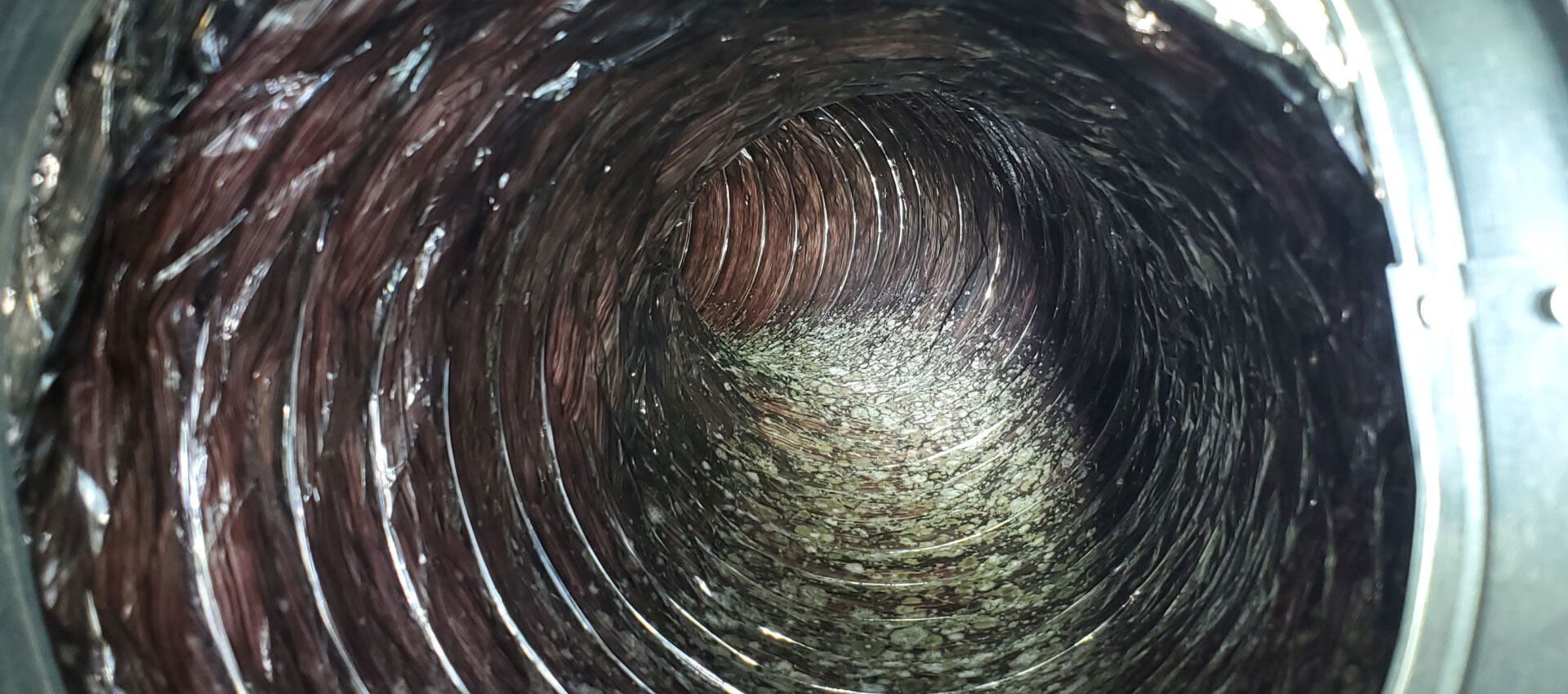 Interior of a flexible HVAC duct with heavy buildup before cleaning